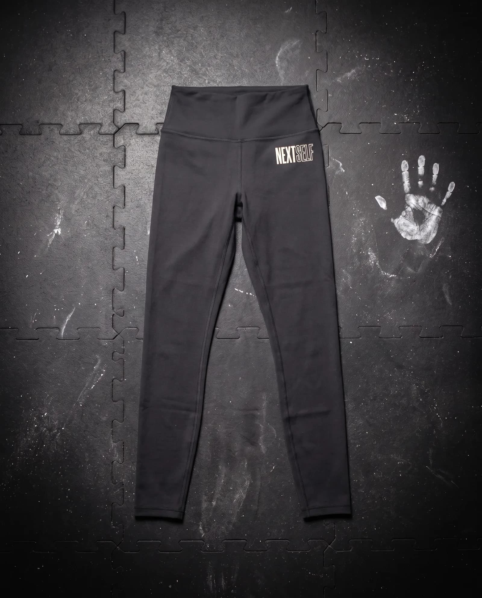 Baseline Legging in Carbon, laid flat on a gym floor