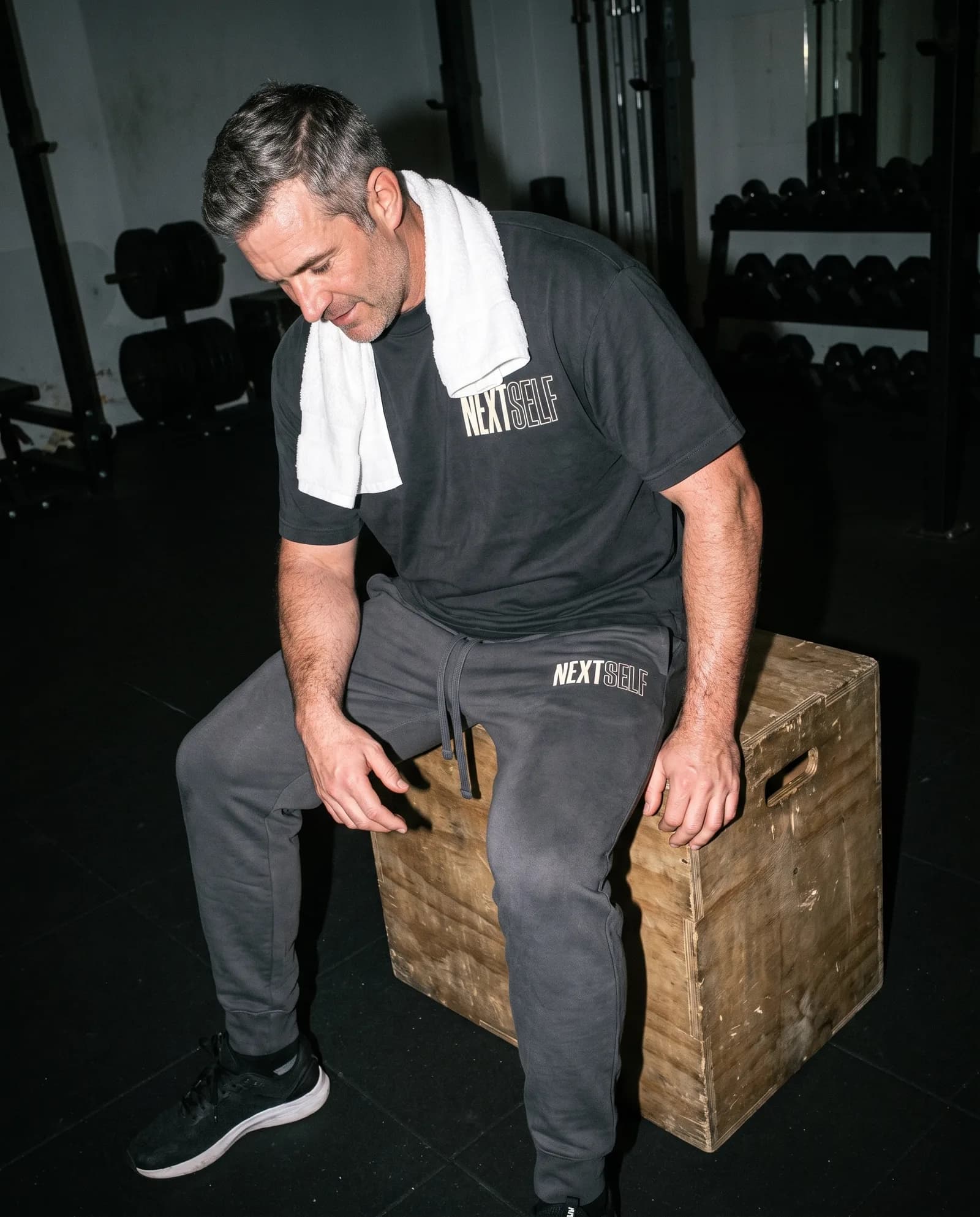 A man resting on a plyo box after a session in the Next Rep Jogger and Foundation Tee